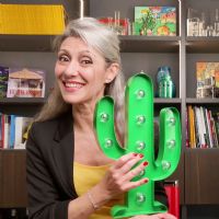 Valeria Sechi seduta davanti a una libreria con in mano una lampada a forma di cactus